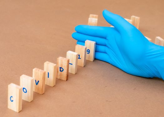 Dominoes spelling out covid being knocked down